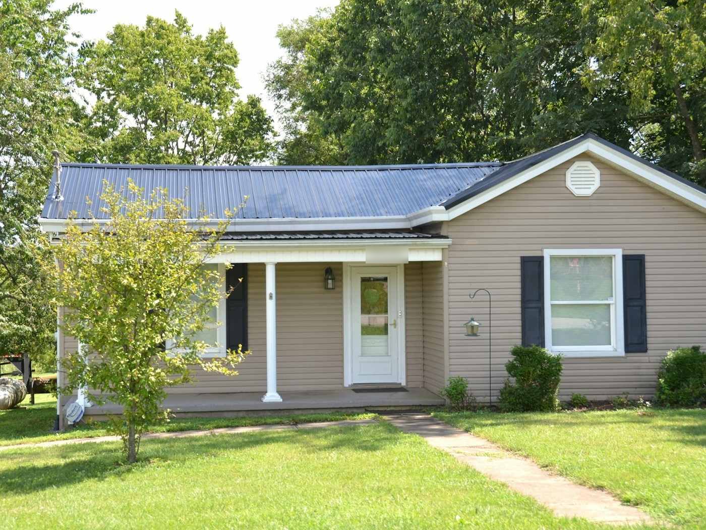 A beige single-story house with a blue metal roof