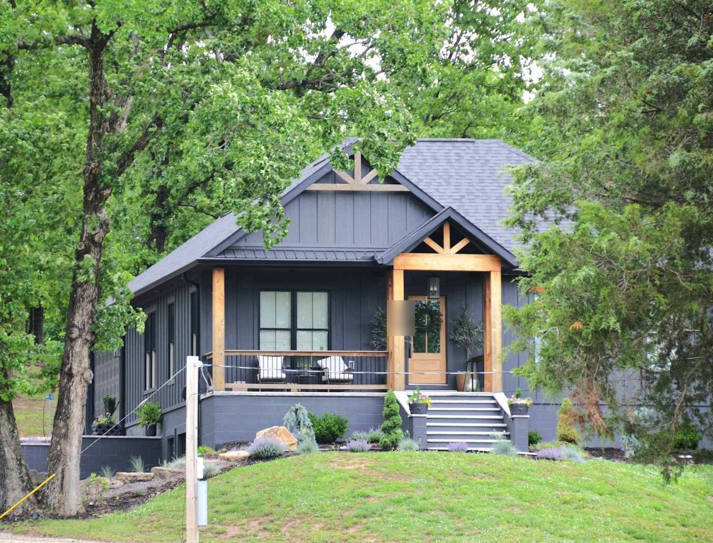 A dark craftsman-style house with a timber front porch
