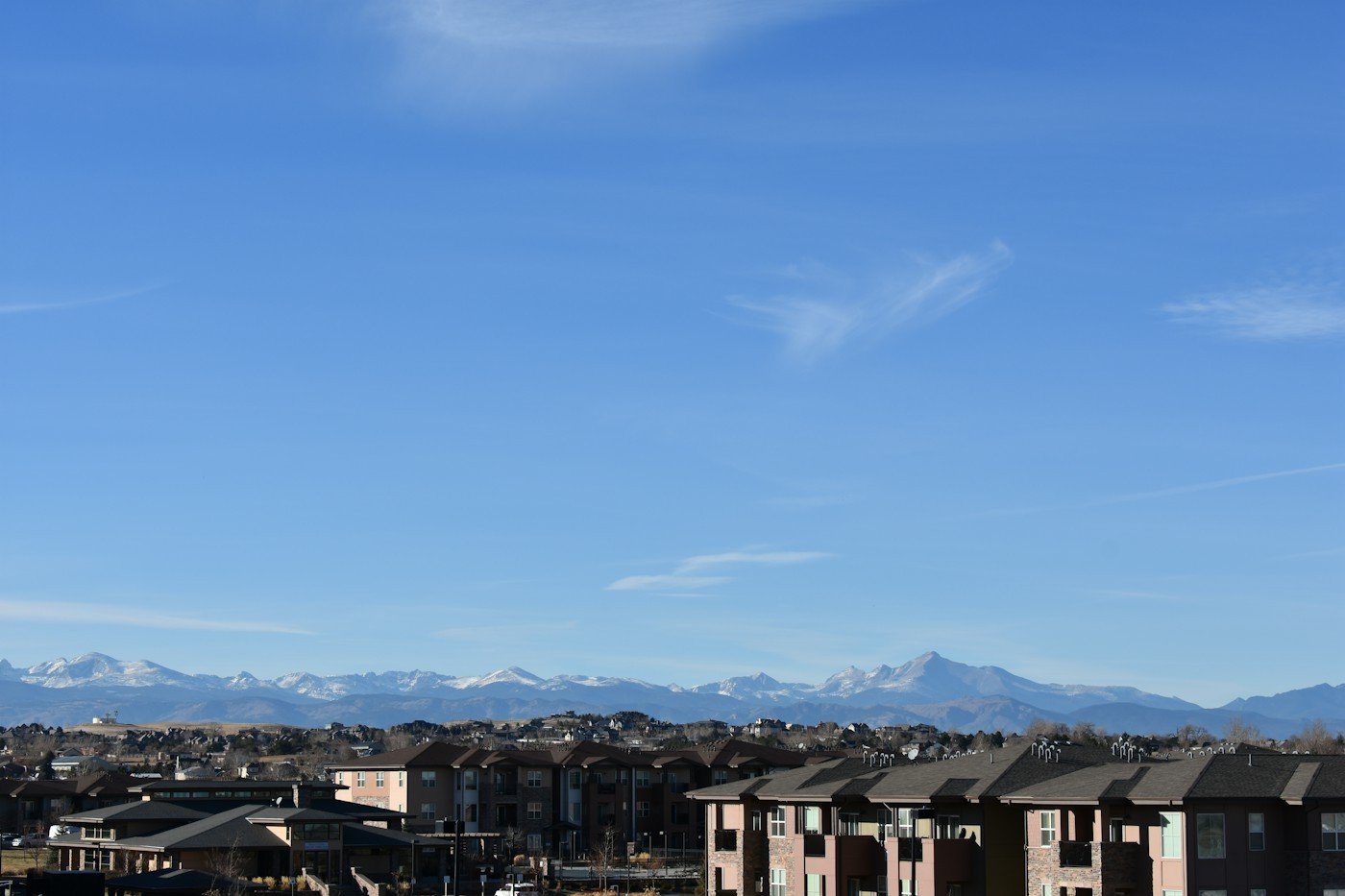 Rooftops in the foreground with snow-capped mountains on the horizon