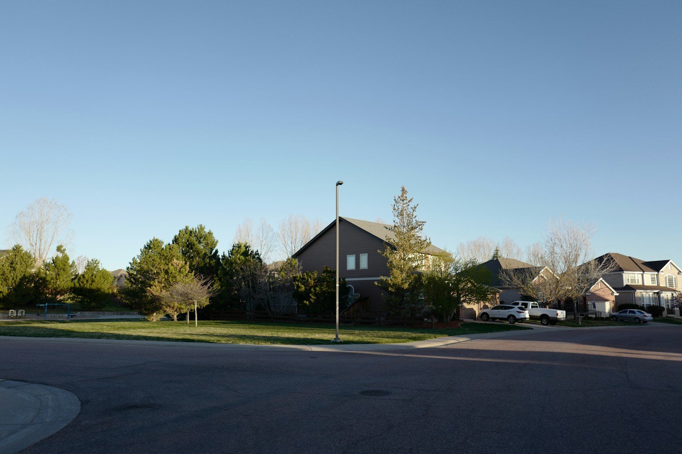 A quiet suburban street with two-story homes in evening light