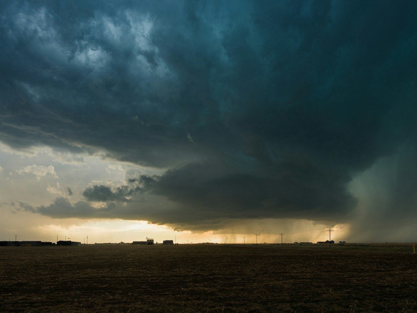 A dark storm cell dropping rain over open plains